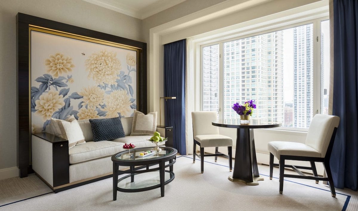 Deluxe guestroom inside Peninsula Chicago - with blue and gold abstract artwork behind sofa