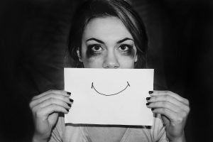 Person hiding their stress and mental health behind a smile